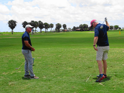 Glen Beaver provides feedback to golf student as they complete one-handed golf swing.