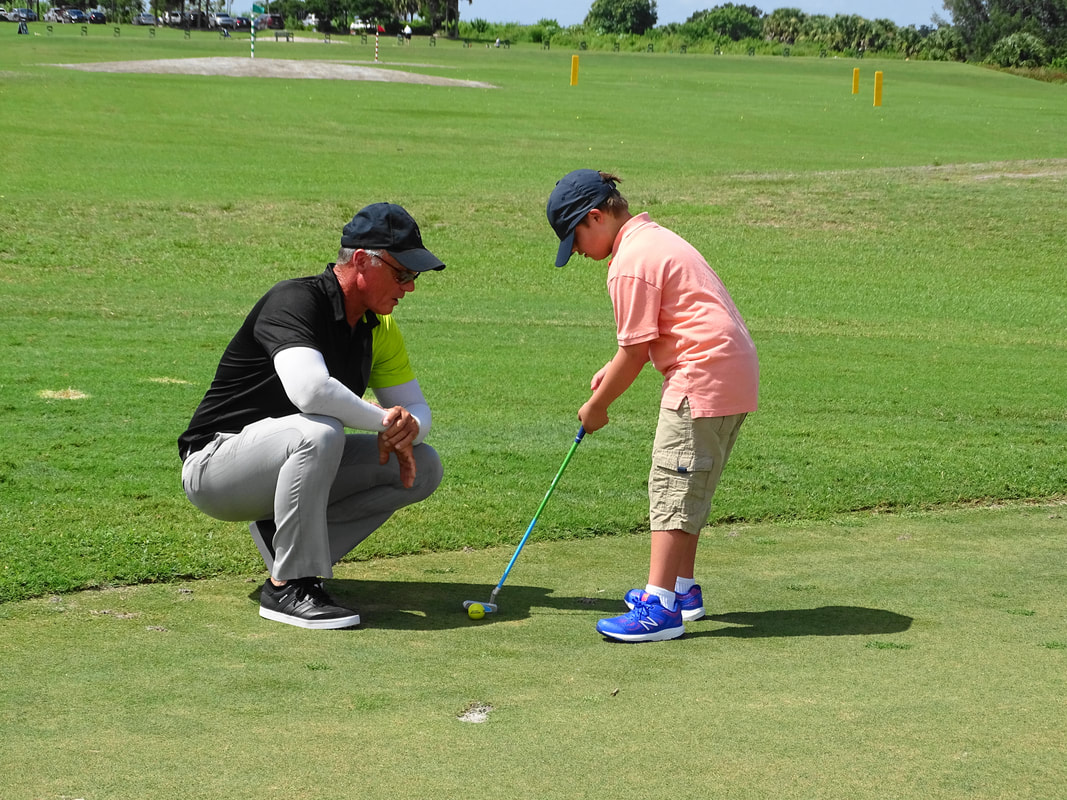Glen Beaver observes junior golf student as they putt.