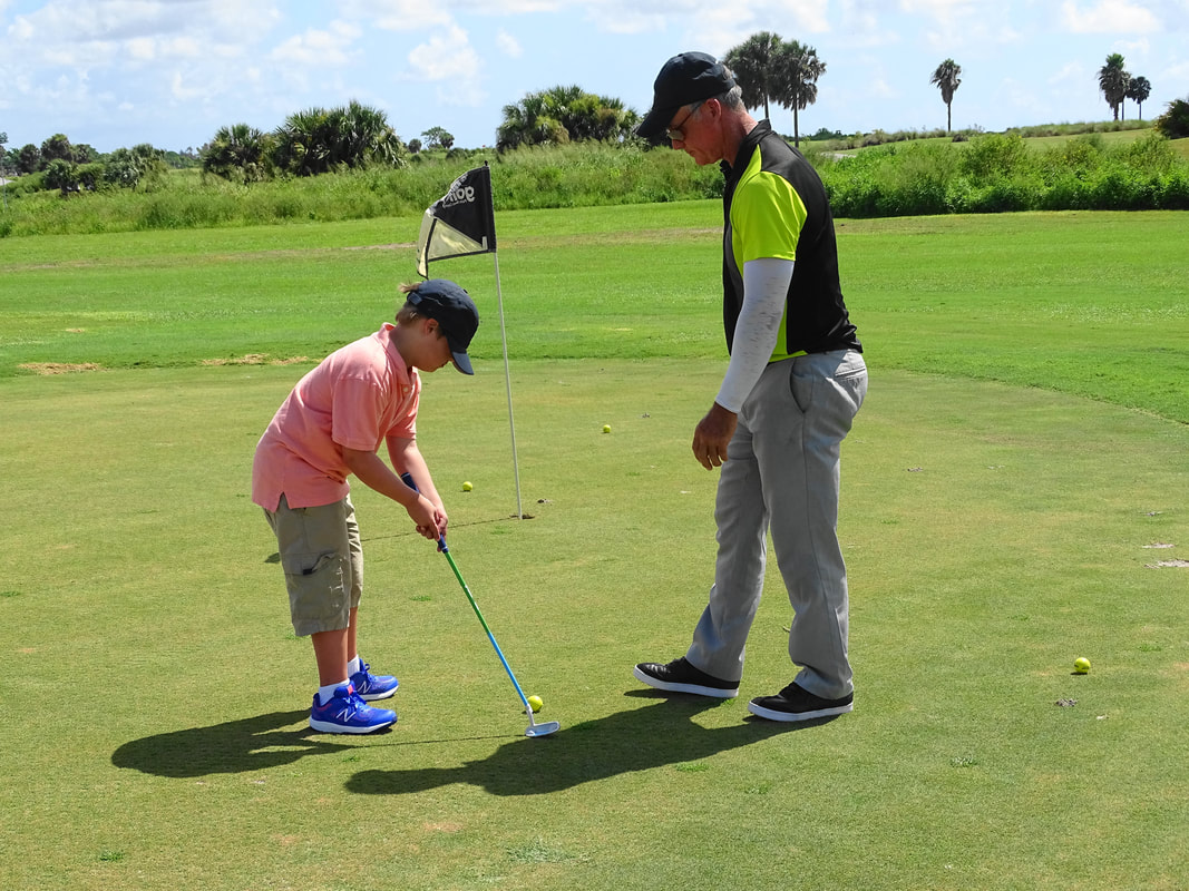 Glen Beaver coaches junior golf student on the putting green.
